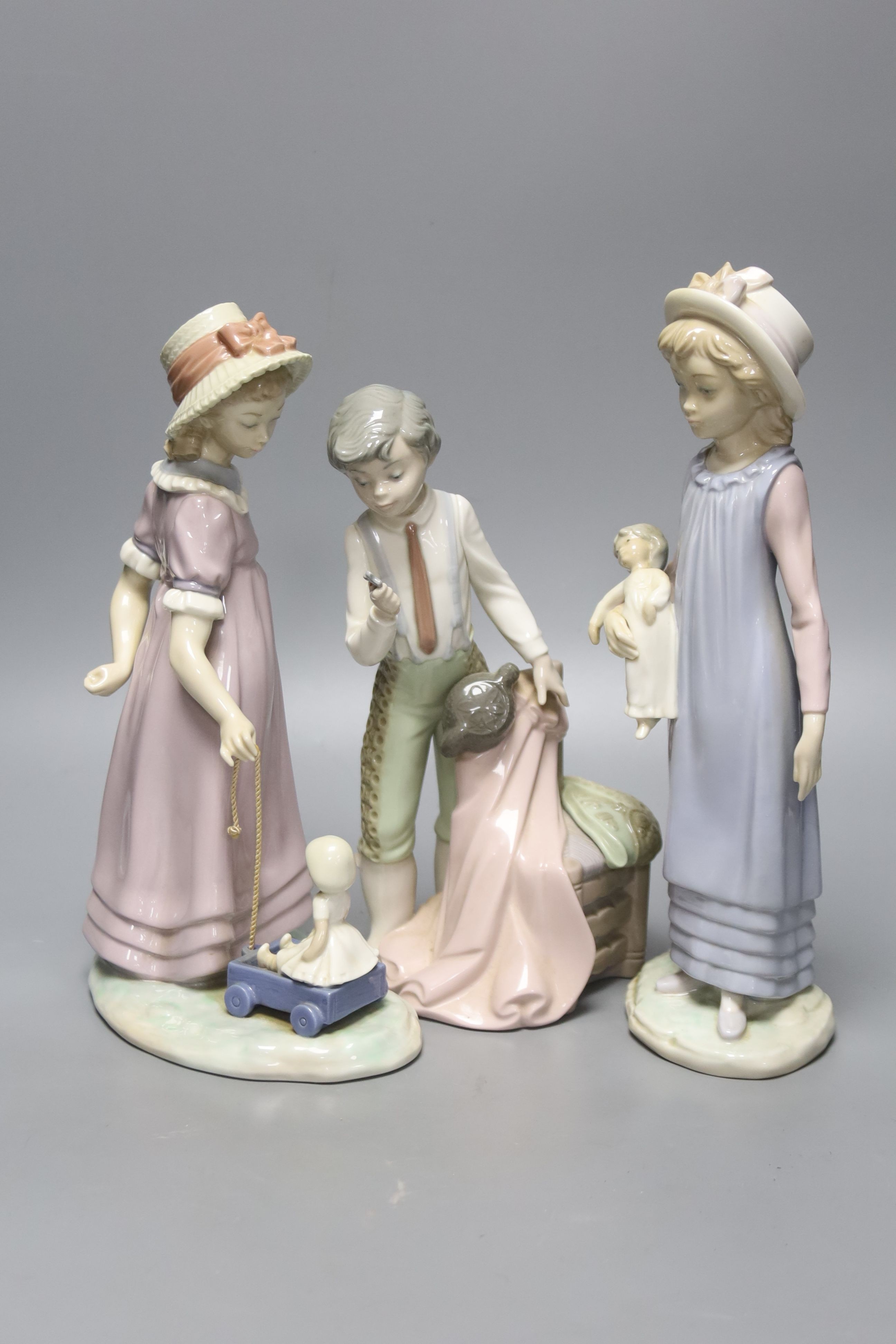 A Lladro figure of a girl with a doll, another girl with a doll in a toy cart and a matador, tallest 28cm